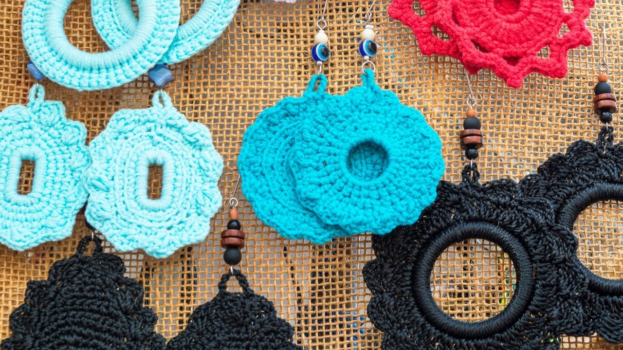 Peças de artesanato do Festival Multicultural em Osasco, com brincos de crochê coloridos.